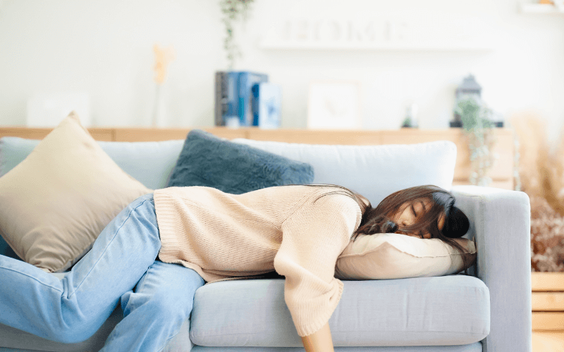 Frau schläft schlecht auf dem Sofa, was zu schlechter Schlaf Entzündungen führen kann.