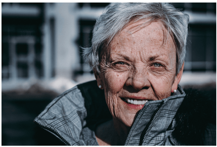 Lächelnde ältere Frau mit grauen Haaren, die Nährstoffe und Demenz in ihrer Gesundheit betont.