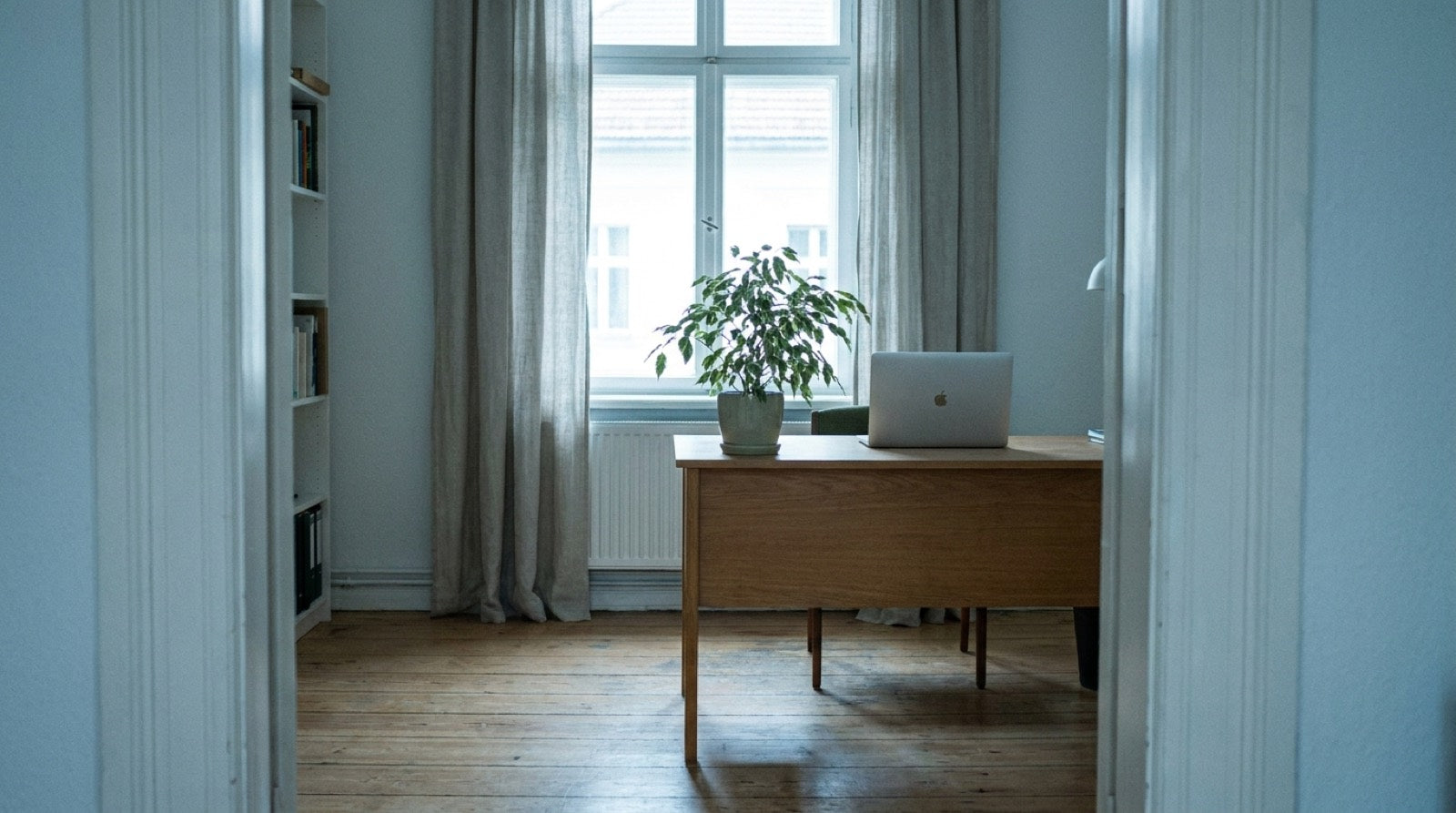 Living room with a wooden table by the window and a bookshelf