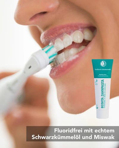 fluoridfreie Zahnpasta mit Schwarzkümmel-Öl in Anwendung, Zähneputzen mit elektrischem Zahnreiniger und Zahnpasta-Tube