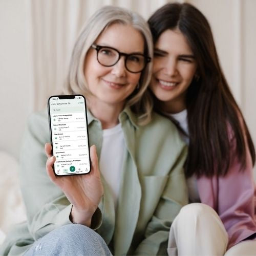 Zwei Frauen sitzen nebeneinander, eine hält ein Telefon mit der Evi-App